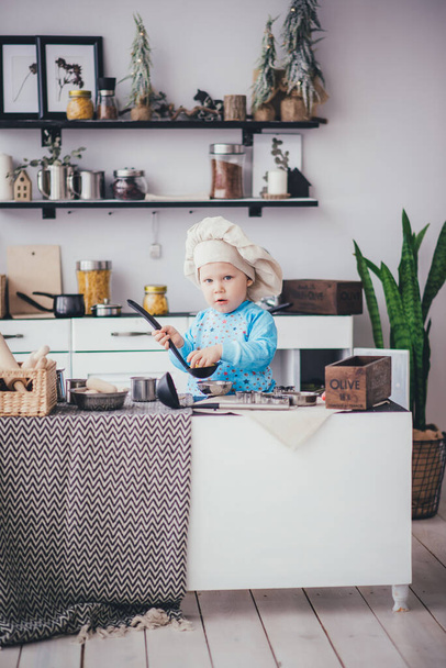 Kid boy in chef's hat and ladle in the kitchen - Фото, зображення