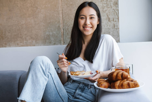 Obrázek usměvavé mladé ženy sedící doma a snídá - Fotografie, Obrázek