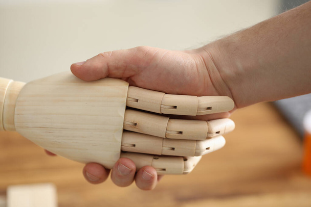 Χειραψία ανθρώπινου χεριού και ξύλινη πρόθεση σε κέντρο αποκατάστασης closeup - Φωτογραφία, εικόνα