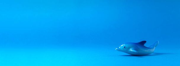 A ceramic dolphin is on a light blue background. - 写真・画像