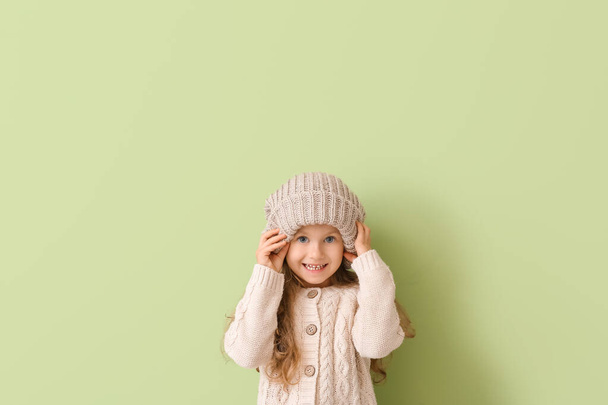 Cute little girl in autumn clothes on color background - Photo, Image