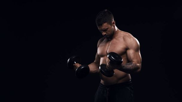 Fit and sporty bodybuilder over black background. Sportsman in studio. Sport and fitness concepts. - Foto, Bild