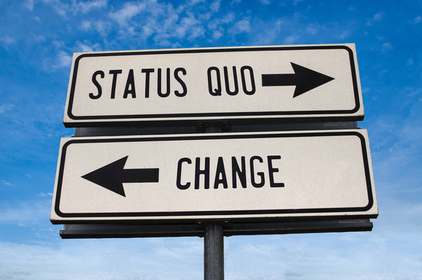 Status quo vs change. White two street signs with arrow on metal pole with word. Directional road. Crossroads Road Sign, Two Arrow. Blue sky background. - Photo, Image
