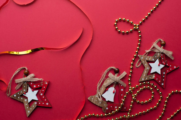 Christmas Wooden Stars, Handbells And Golden Beads on Red Background. - Photo, Image