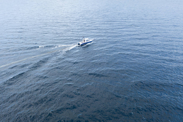 Aerial view fisherman on boat at the ocean. Top view beautiful seascape with the fishing boat. Aerial view fishing motor boat with angler. Ocean sea water wave reflections. Motor boat in the ocean. - Фото, зображення