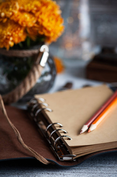 Cuaderno abierto de artesanía vacía y flores de crisantemo naranja sobre fondo rústico. Tarjeta de felicitación con espacio de copia para su texto - Foto, imagen