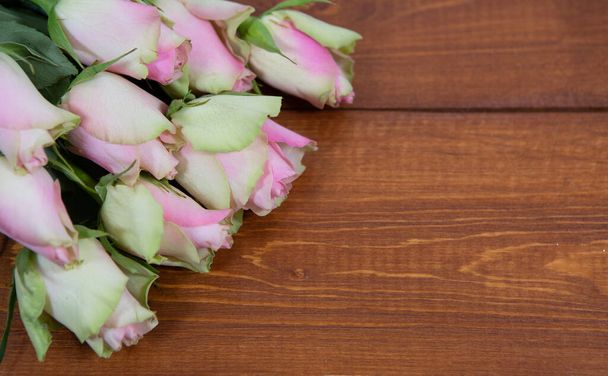 A beautiful bouquet of soft pink roses with unadorned buds on a dark wooden background. - Photo, image