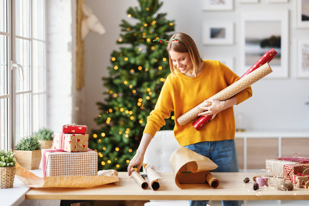 onnellinen nuori nainen valmistautuu jouluun ja pakkauslahjaan - Valokuva, kuva