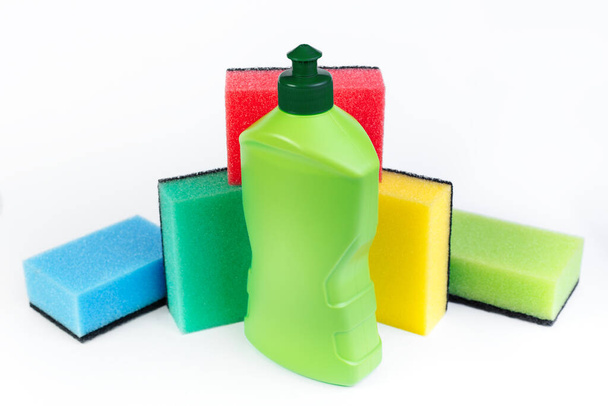 Bottle of dishwashing detergent and colorful sponges on white background. - Fotografie, Obrázek