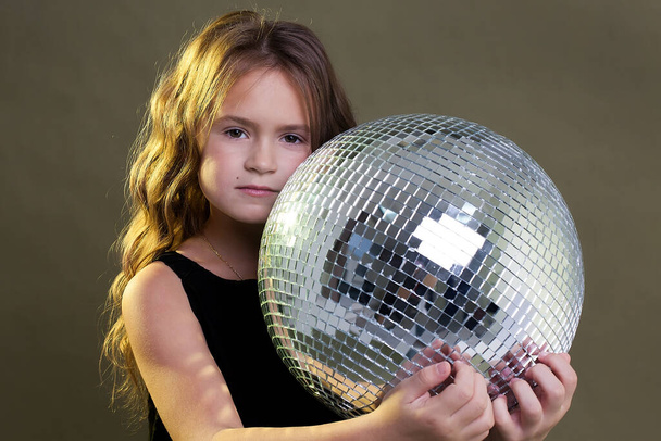little happy baby girl holding a disco ball on a gray background. new year. - Foto, immagini