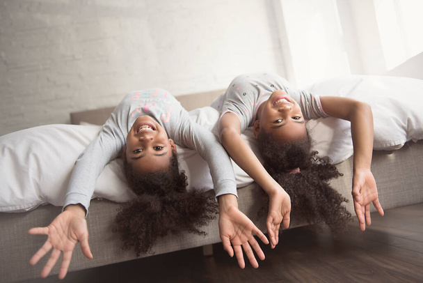 Two little african american girls on bed at home - Foto, imagen