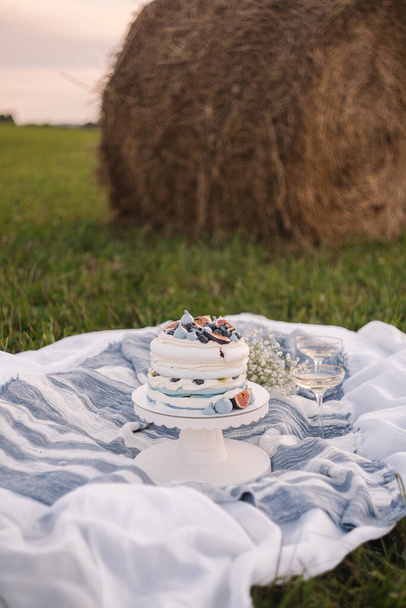 Pavlova cake with meringues, blueberries and figs in a field with wildflowers - Foto, afbeelding
