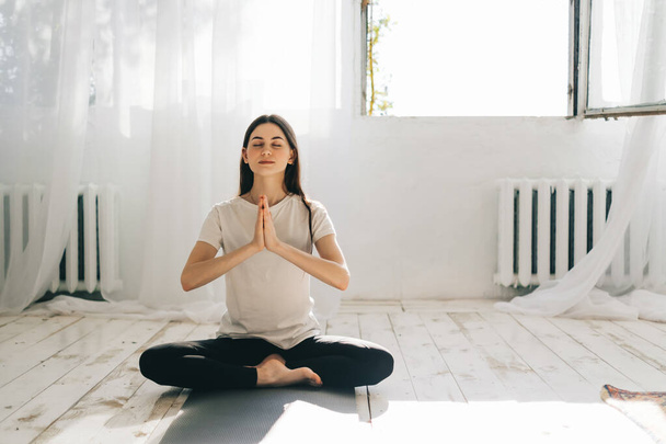 Güzel esmer kadın meditasyon yapıyor, evde yoga yapıyor. Formda ve sağlıklı kalmak. - Fotoğraf, Görsel