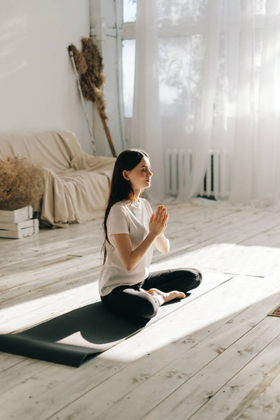 Beautiful brunette fitness woman meditate, doing yoga indoors at home. Staying fit and healthy - Foto, immagini