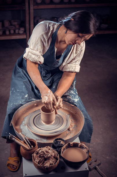 Bella ceramista professionista sta lavorando sulla ruota ceramica. Lavoro manuale. - Foto, immagini