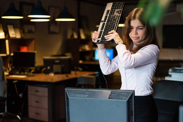 Nervous breakdown at work. Business woman freaks out and breaks the computer in the office - Fotografie, Obrázek
