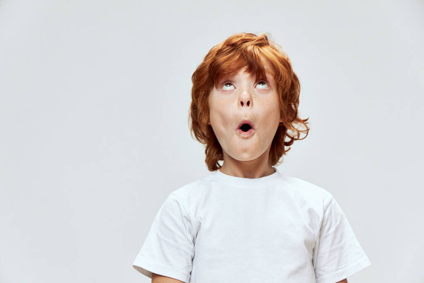 surprised boy with open mouth looking up white t-shirt cropped - Фото, изображение