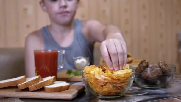 Hungry Kid Hand bierze chrupiące Golden Potato Chips z płyty. Śmieciowe jedzenie w kolacji - Materiał filmowy, wideo