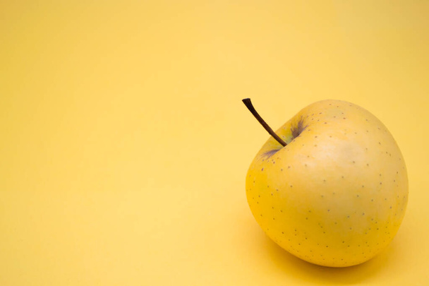 Manzana dorada grande de color amarillo anaranjado sobre fondo amarillo anaranjado. Copiar espacio. - Foto, imagen