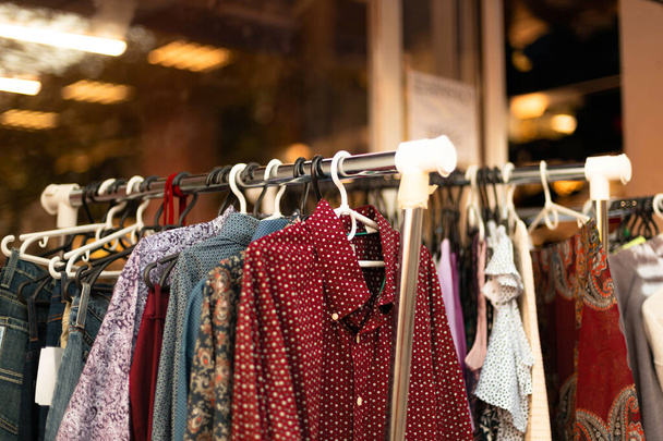 Zakupy w sklepie. Kolorowe modne ubrania na wieszaki w sklepie na sprzedaż - Zdjęcie, obraz