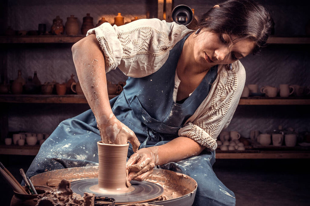 Beautiful artisan works with clay on a potters wheel. Manual work. - Photo, Image