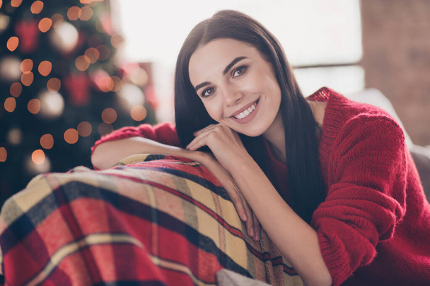 Photo of pretty young girl lay head hands toothy smile look camera wear red pullover in decorated living room indoors - Photo, Image