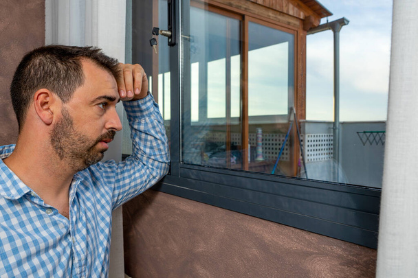 Surullinen parrakas mies katselee ikkunasta. Hän näyttää huolestuneelta, masentuneelta, ajattelevaiselta ja yksinäiseltä. Masennuksen käsite - Valokuva, kuva