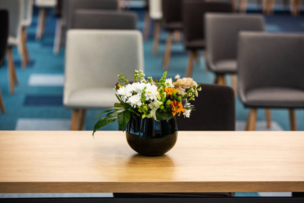 Table de travail avec vase de fleurs dans un bureau moderne. Bouquet de fleurs sur une table dans une chambre moderne. - Photo, image
