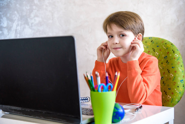 子供たちは家で宿題をする。少年たちはノートパソコンを見ている。学校に戻る。遠隔オンライン教育. - 写真・画像