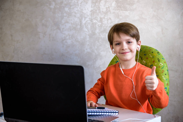 子供たちは家で宿題をする。少年たちはノートパソコンを見ている。学校に戻る。遠隔オンライン教育. - 写真・画像