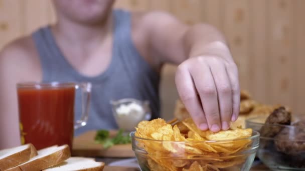 Hungry Kid Hand nimmt knusprige Golden Potato Chips vom Teller. Junk Food beim Abendessen - Filmmaterial, Video