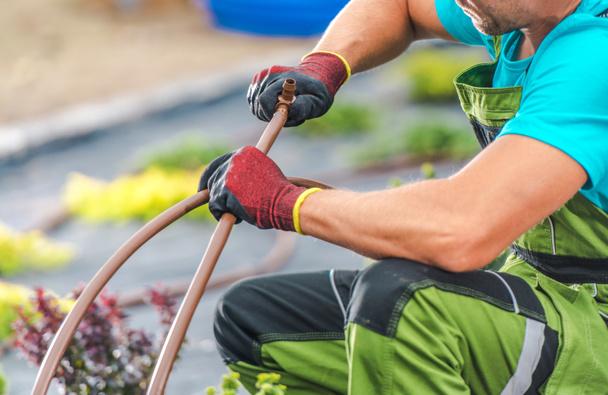 Καυκάσιος επαγγελματίας κηπουρός που συνδέει πλαστικά στοιχεία σωληνώσεων του συστήματος άρδευσης κήπων. Τεχνολογίες κήπου. - Φωτογραφία, εικόνα