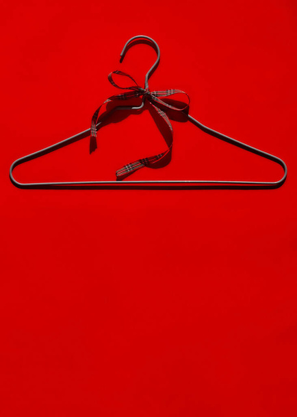 IJzeren hanger met strik op rode achtergrond. Verkoop concept. Zwarte vrijdag. Ruimte voor tekst. - Foto, afbeelding