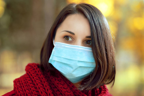 Krásná mladá žena portrét v lékařské ochranné masky obličeje procházky venku v podzimním parku. Koncept uzamčení koronaviru - Fotografie, Obrázek
