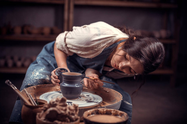 Elegante scultore professionista vasaio lavora con argilla su una ruota Potters e al tavolo con gli strumenti. Produzione artigianale. - Foto, immagini