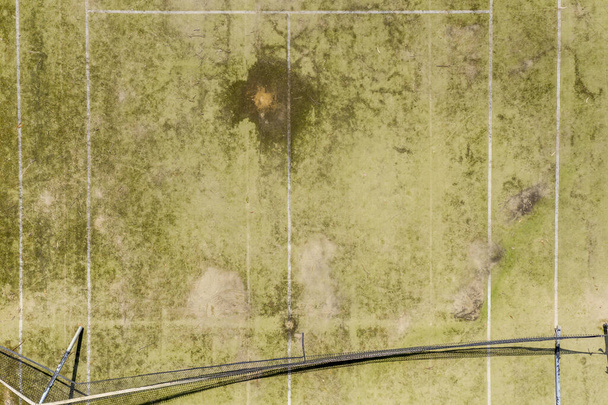 Uma vista aérea de um antigo campo de ténis não utilizado em mau estado num parque público numa pequena cidade regional - Foto, Imagem
