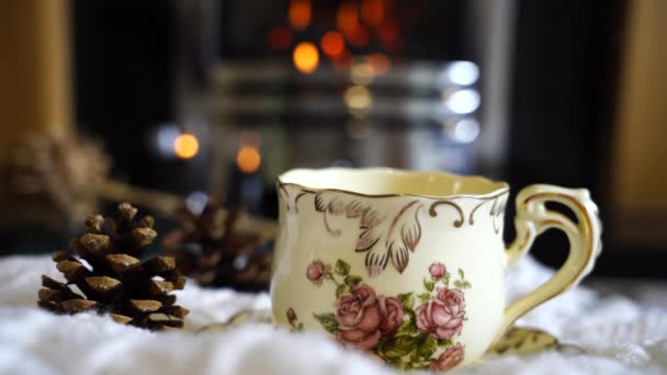 Caffè caldo o tazza di tè con vapore con camino sfocato sullo sfondo del soggiorno, scena accogliente e rilassante per fare colazione in giornata cupa in autunno o inverno, tradizionale inglese - Filmati, video