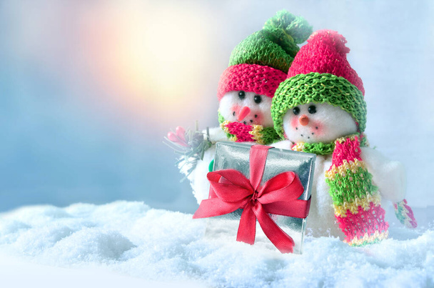 Kaksi hauskaa lumiukkoa lahjapakkauksella talvella lumessa. Loma-ajatus. - Valokuva, kuva