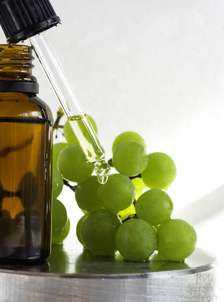 Szőlőmag olaj egy üvegben érett zöld szőlő, olaj csöpögő pipetta. Tiszta esszenciális bőrápoló olaj. Alternatív gyógyászat vagy Spa kezelési koncepció. Szelektív fókusz. Fénymásolási hely - Fotó, kép