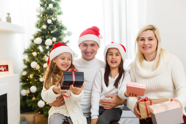 Ευτυχισμένη οικογένεια παίζει με δώρα Χριστουγέννων στο σπίτι - Φωτογραφία, εικόνα