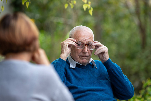 Portret van een oudere man die met zijn vrouw praat in het park. - Foto, afbeelding