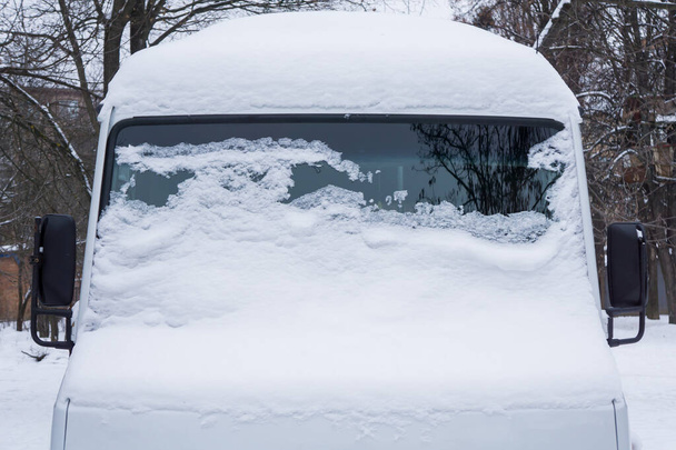 Le pare-brise du minibus gelé est recouvert de glace et de neige par une journée d'hiver. Gros plan. - Photo, image