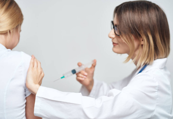 Женщина-врач в медицинском платье делает инъекцию пациенту - Фото, изображение