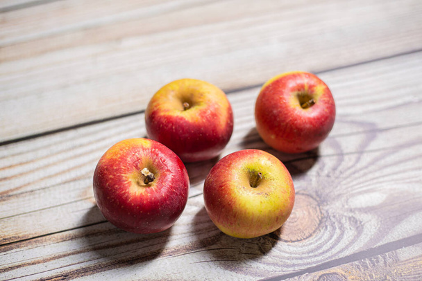 Four red and yellow autumn apples fruit on a wooden surface - Фото, изображение