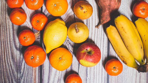 Ahşap bir yüzey üzerinde mandalina, elma, armut ve muz gibi birçok portakal sonbahar meyvesi - Fotoğraf, Görsel