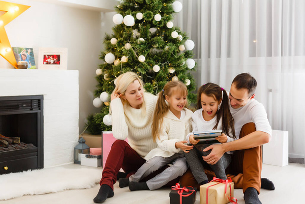 família feliz pai mãe e filhos sentados à lareira na véspera de Natal - Foto, Imagem