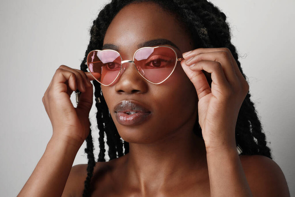 Young black woman wearing pink sunglasses. Skin care concept. - 写真・画像