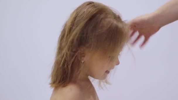 髪の乾燥プロセス。お母さんはかわいい幸せな金髪の娘のヘアドライヤーで髪を乾かします。ヘアケア。子育てだ。フルHD映像 - 映像、動画