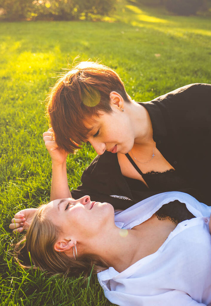 Verliebte Mädchen liegen an einem sonnigen Tag im Gras in einem Park.  - Foto, Bild