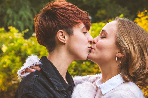 Девушки влюблены обнимаются целуясь в парке в солнечный день. - Фото, изображение